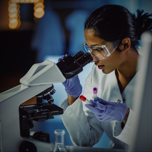 Young woman scientist looking in microscope