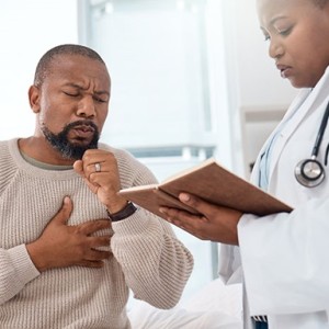 Man coughing next to doctor