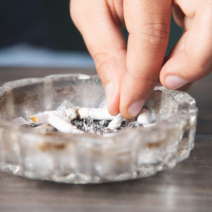 Hand stubbing out a cigarette in an ashtray